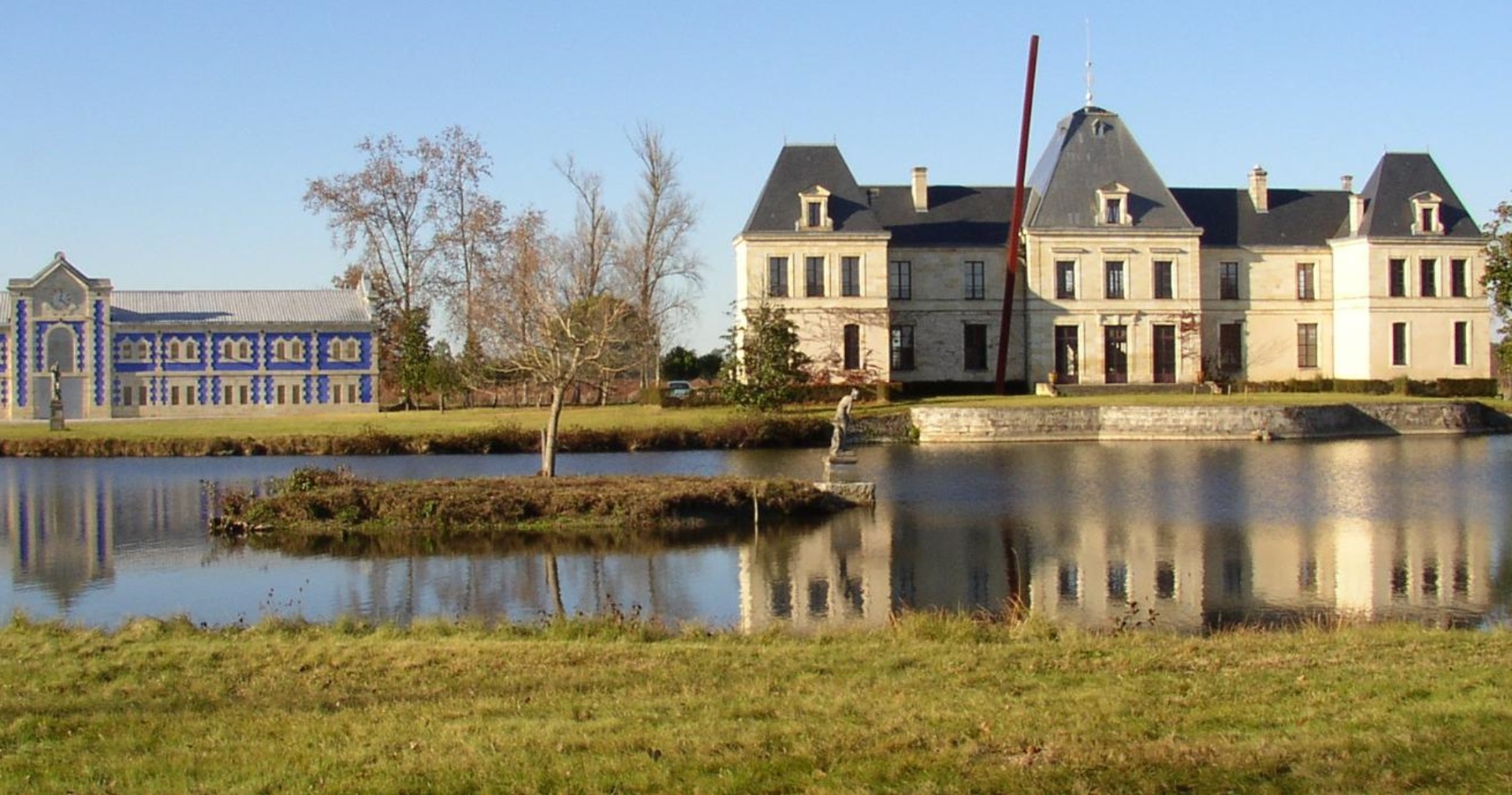 Château viticole bordelais et son chai décoré, reflets dans le bassin