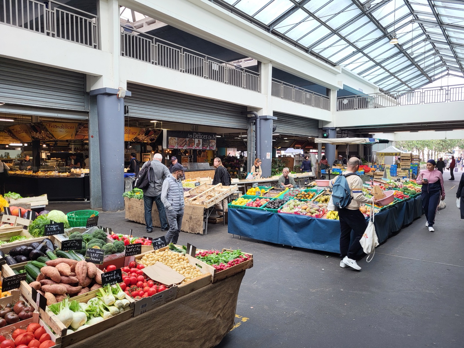 Vue intérieure du Marché des Capucins de Bordeaux, avec ses étals de légumes et de fruits et sa toiture en verre